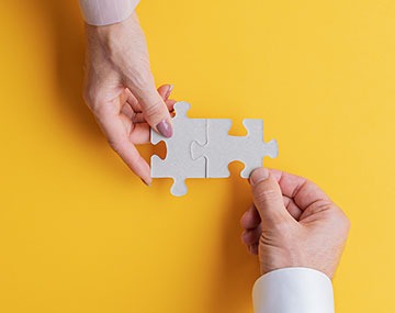 Hands joining jigsaw puzzle pieces